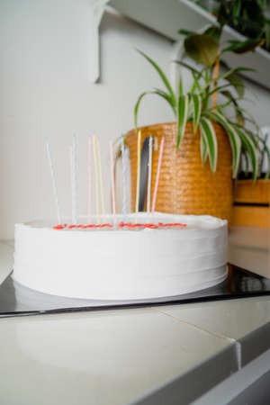 White cake with candles and blank background space on black cake board and wooden greenery background, birthday cake mockupの写真素材