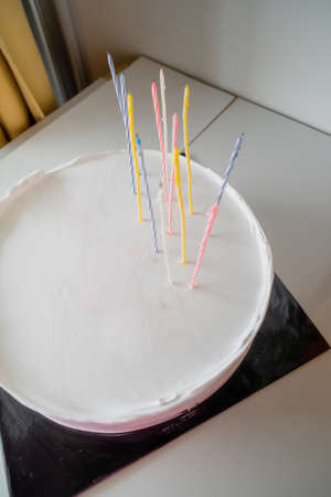White cake with candles and blank background space on black cake board and wooden greenery background, birthday cake mockupの写真素材