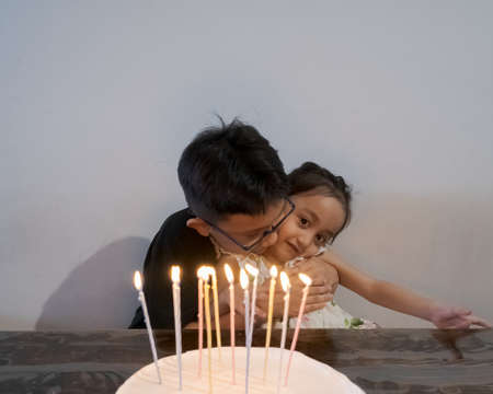 Children celebrating birthdays together. Brother hugging baby sister.の写真素材