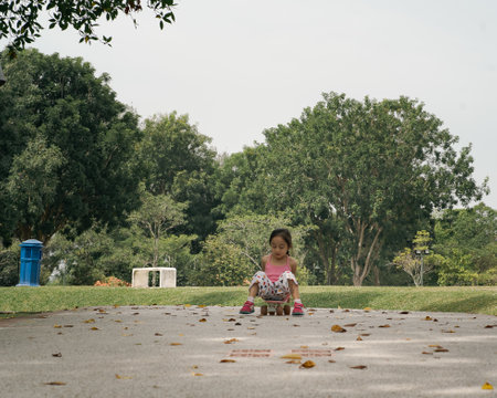Bangi, Malaysia - Oct 16, 2021 Child riding skateboard in the park. Little girl learning to ride skate board.のeditorial素材