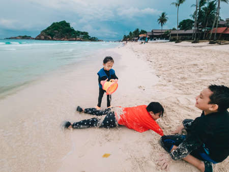 Children play in the sand at the beach.の写真素材