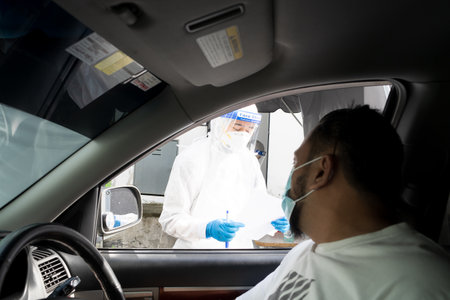 Bangi, Malaysia - Feb 15, 2022: Healthcare worker is performing a PCR swab test by drive thru lab.のeditorial素材