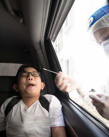 A young boy is taking a PCR swab test by drive thru lab.のeditorial素材