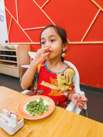 Putrajaya, Malaysia - July 20, 2022 Child eating edamame beans at Sushi Kings, Malaysia.のeditorial素材