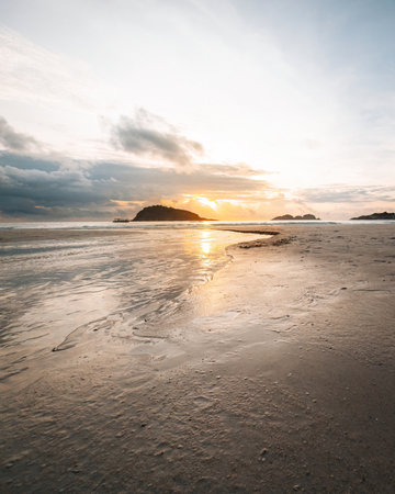 Sunrise reflections on the beach sand. Textured and watery sandy beach.の写真素材