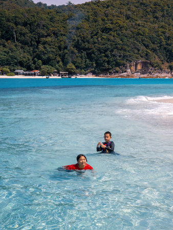 Children swimming at the beach together in a sunny day.の写真素材