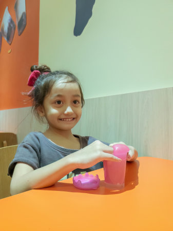 little girl playing with pink shiny slime on the table at the restaurant.の写真素材