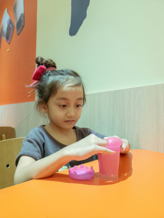 little girl playing with pink shiny slime on the table at the restaurant.の写真素材
