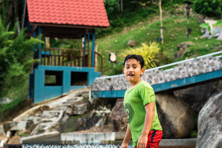 The boy wet and standing on the pool is near the resort.の写真素材