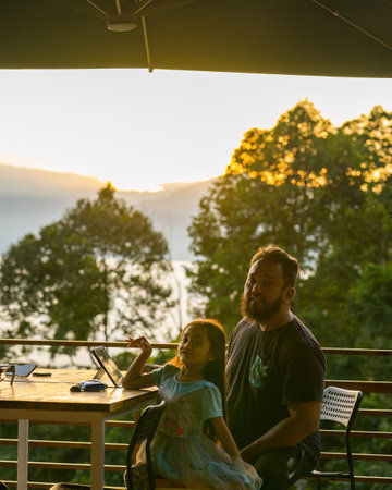 Family having alfresco breakfast during sunrise on the wooden patio.の写真素材