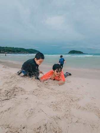 children playing sand at the beach together.の写真素材