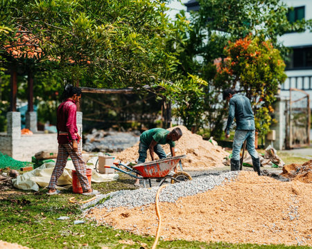 Selangor, Malaysia - October 21, 2023Man mixing concrete with shovel on the floor by hand at a house renovation constructions.のeditorial素材