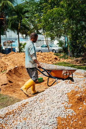 Selangor, Malaysia - October 21, 2023 Workers using wheelbarrow at a house renovation constructions.のeditorial素材