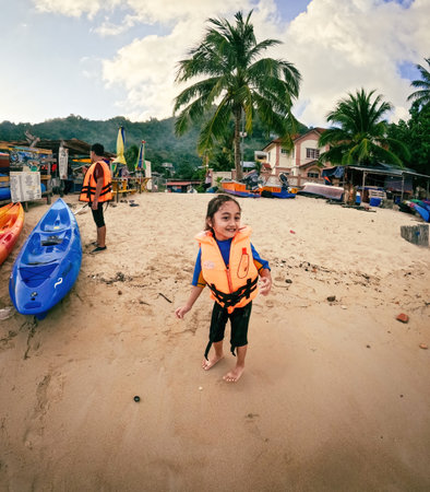 Terengganu, Malaysia - March 16, 2023 Little girl wearing life jacket and smiling before going on the kayak.のeditorial素材