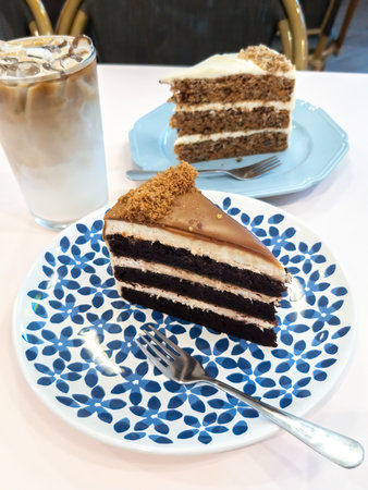 Red velvet and carrot cakes on the table with iced latte for tea time.