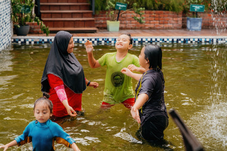Happy Family swimming in the pool. Mother wearing hijab with children.の写真素材