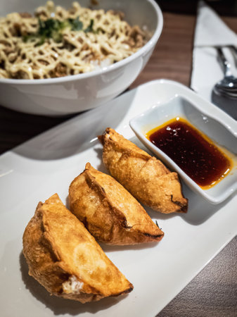 Fried dimsum with soy sauce dipping and ramen noodles in the background.の写真素材