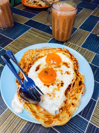 Roti sarang burung, a pratha looks like bird nest with half cook eggs in the middle served with teh tarik as staple breakfast in Malaysia.の写真素材