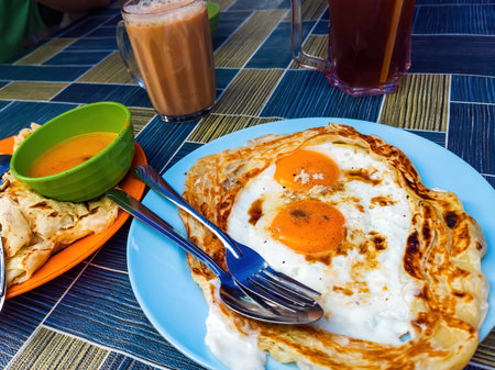Roti sarang burung, a pratha looks like bird nest with half cook eggs in the middle served with teh tarik as staple breakfast in Malaysia.の写真素材