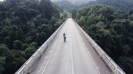 Aerial view of motorcycles on the elevated road across the rainforest mountains in Hulu Selangor, Malaysia.の写真素材