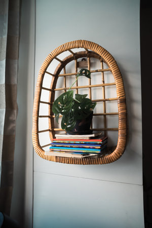 Rattan shelf filled with ornamental plants on the wall. A beautiful shelf that brings nature indoors with warm earthy tones, handmade from rattanの写真素材