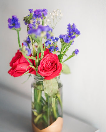A bouquet of fresh roses with baby breath in a glass water jar on white background.の写真素材