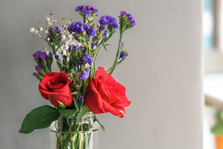 A bouquet of fresh roses with baby breath in a glass water jar on white background.の写真素材