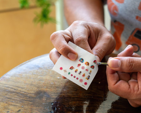 Bangi, Malaysia - July 17, 2021 Taking out a nail sticker from the sheet to apply on nails.のeditorial素材