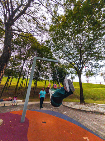 Happy family playing swing outdoors in the garden. Beautiful park.