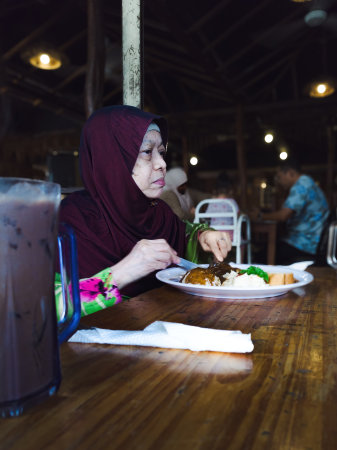 An Asian senior woman is eating a healthy lunch at the restaurant.の写真素材
