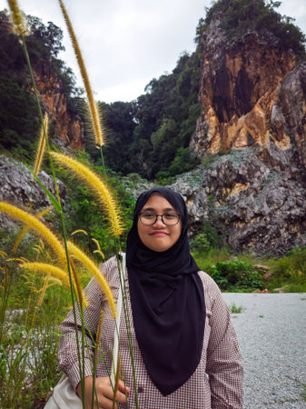 Teenager wearing glasses standing behind the tall grass in nature.の写真素材