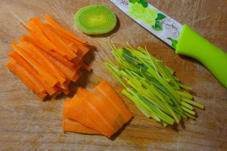 Background with sliced pork carrots and kitchen knife. The vegetables are cut into different shapes on an old scratched wooden kitchen board.の写真素材