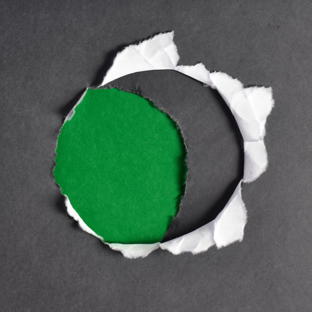 Green hole in torn paper. Fillet. Irregular shape blank round tag with torn edge frame on black crumpled background.の写真素材