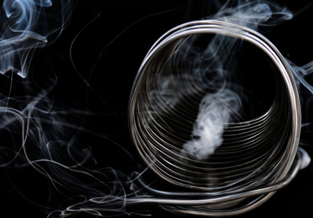 A spiral of burning conductive wire. Coil of galvanized damaged metal with smoke. Technology, danger.の写真素材