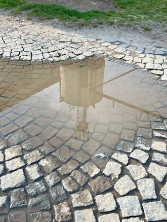 Reflection of a puddle between paving granite tiles with an old water tower.の写真素材