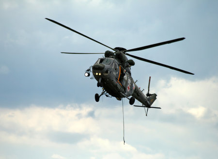 Rescue medical helicopter of the Czech Republic Army. Military medical helicopter in action with a rescuer descending on a rope. Helicopter in flight at an airshow.の写真素材