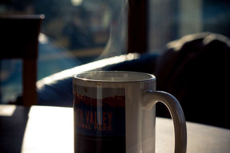 A mug of coffee steams in the morning sunlightの写真素材