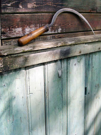 Sickle on wall of the old wooden houseの写真素材
