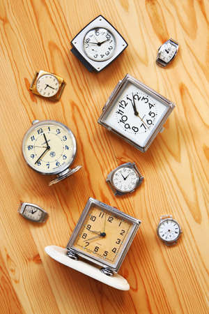 The old alarm clocks, watches  lying on a wooden surface