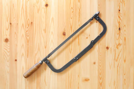 Old hacksaw on wooden surfaceの写真素材