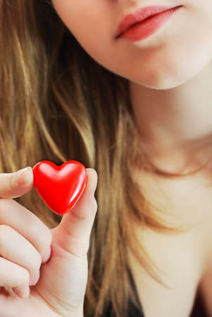 Girl holds in her hand a small red heart.の写真素材