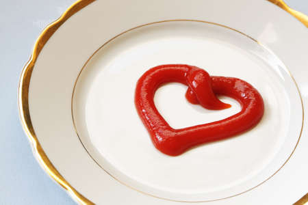 Tomato paste in the form of a heart on dinner plateの写真素材