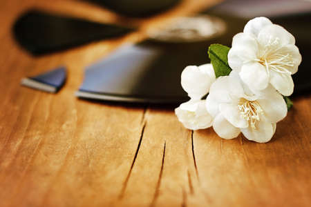 Artificial flowers of  jasmine on a broken gramophone record. Image on a wooden background.