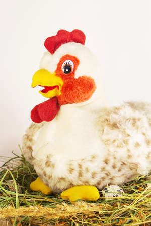 Toy chicken on hay on a light backgroundの写真素材