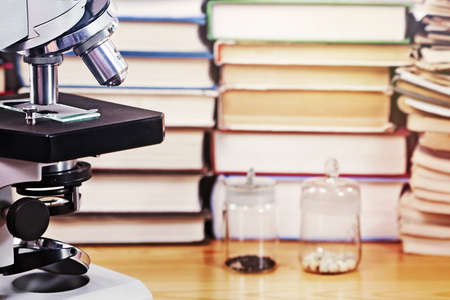 Microscope and test specimens against a background of scientific booksの写真素材