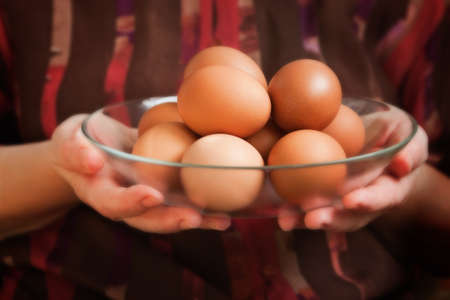 A glass dish with fresh brown chicken eggs in woman handsの写真素材