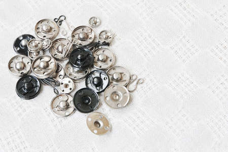 Group of various metal snap-fastenes and hooks on the vintage cotton fabric and text space
