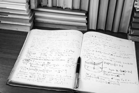 Open writing-book with mathematical lectures against a background of booksの写真素材