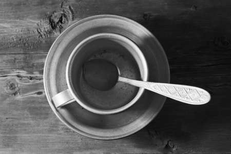 Empty aluminum dish, spoon and mug on the old wooden table, black and whiteの写真素材