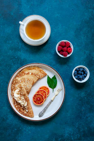 Delicious homemade pancakes with raspberries, blueberries and bloody orange fruit on classic blue...